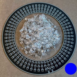May include: A black circular circuit board with a ring of small holes around the edge. A large pile of clear LED lights are in the center of the board. A blue circle is in the lower right corner of the image.