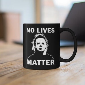 May include: Black coffee mug with a white graphic of Michael Myers from the Halloween franchise. The text "NO LIVES MATTER" is printed in white on the mug.