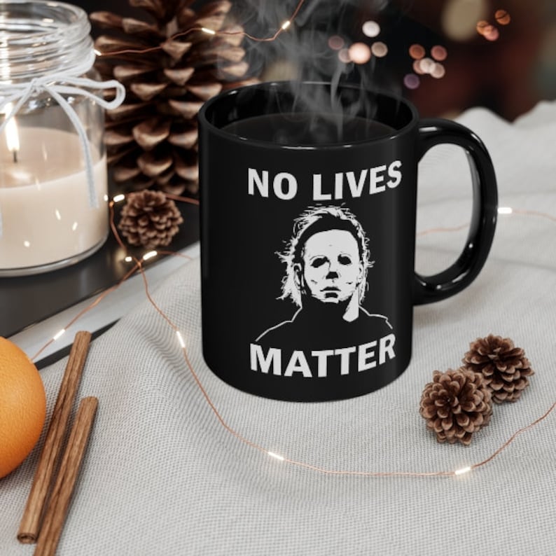 May include: Black coffee mug with a white graphic of Michael Myers from the Halloween movies. The text "NO LIVES MATTER" is printed in white on the mug.