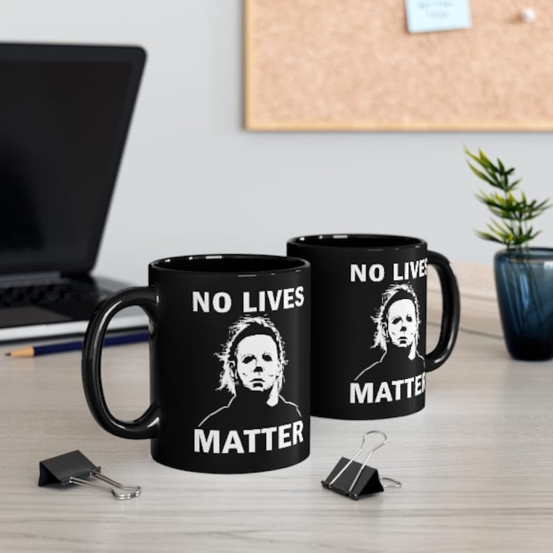 May include: Two black ceramic mugs with white text and a graphic of a horror movie character. The text on the mugs reads "No Lives Matter".