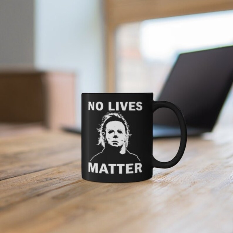 May include: Black coffee mug with a white graphic of Michael Myers from the Halloween franchise. The text "NO LIVES MATTER" is printed in white on the mug.