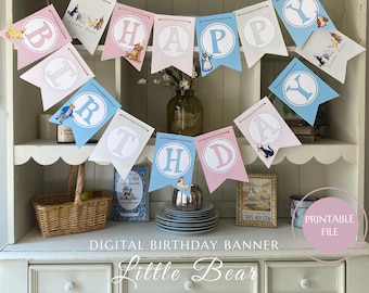 May include: A decorative "Happy Birthday" banner with pink, blue, and white pennants, displaying the text "Little Bear". Each pennant features a letter and a cartoon illustration. The banner is suspended above a white cabinet.