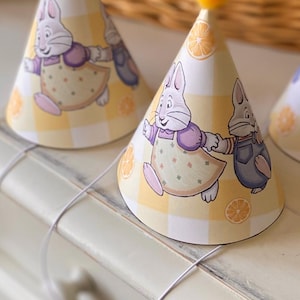 May include: Party hats with a yellow and white checkered pattern, featuring cartoon rabbit characters and orange slice illustrations. Each hat is topped with a yellow pom-pom.