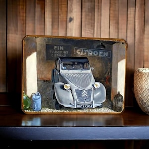 May include: A vintage metal sign depicting a grey Citroen car in a garage. The sign includes the text "CITROEN" and "FIN PARCOURS CHRONO". The sign has a distressed appearance, with a wooden background, evoking a sense of nostalgia.