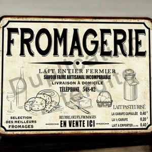Puede incluir: Letrero metálico de estilo vintage con la palabra "FROMAGERIE" en letras negras grandes. El letrero presenta ilustraciones de queso, mantequilla y productos lácteos, junto con texto en francés. El letrero tiene un aspecto envejecido.