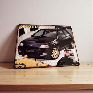 Puede incluir: Letrero metálico vintage con un coche Renault negro con ruedas doradas. El letrero tiene el texto "Renault" y "Williams". El fondo es un diseño descolorido con un casco de carreras.