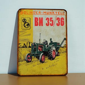 May include: Vintage metal sign featuring a green and red tractor in a field. The sign has the text "BOLINDER-MUNKTELL" and "BM 35/36" in red. The background is yellow and depicts a rural scene.