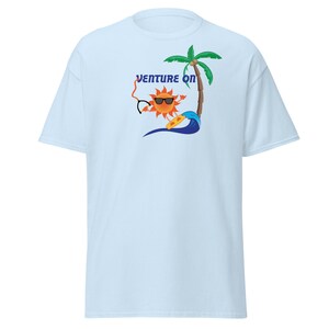 May include: Light blue t-shirt featuring a cartoon sun wearing sunglasses and holding a surfboard. The sun is in front of a palm tree and a wave. The text "Venture On" is above the sun.