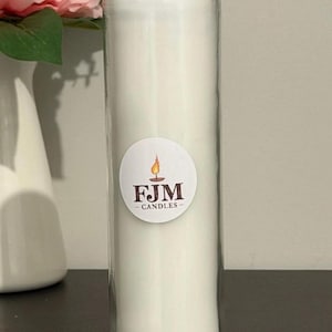 May include: A tall, cylindrical clear glass candle holder filled with solid white wax. A circular white sticker is centred on the glass, featuring a graphic of a lit candle flame above the brown text FJM - CANDLES in a serif font.