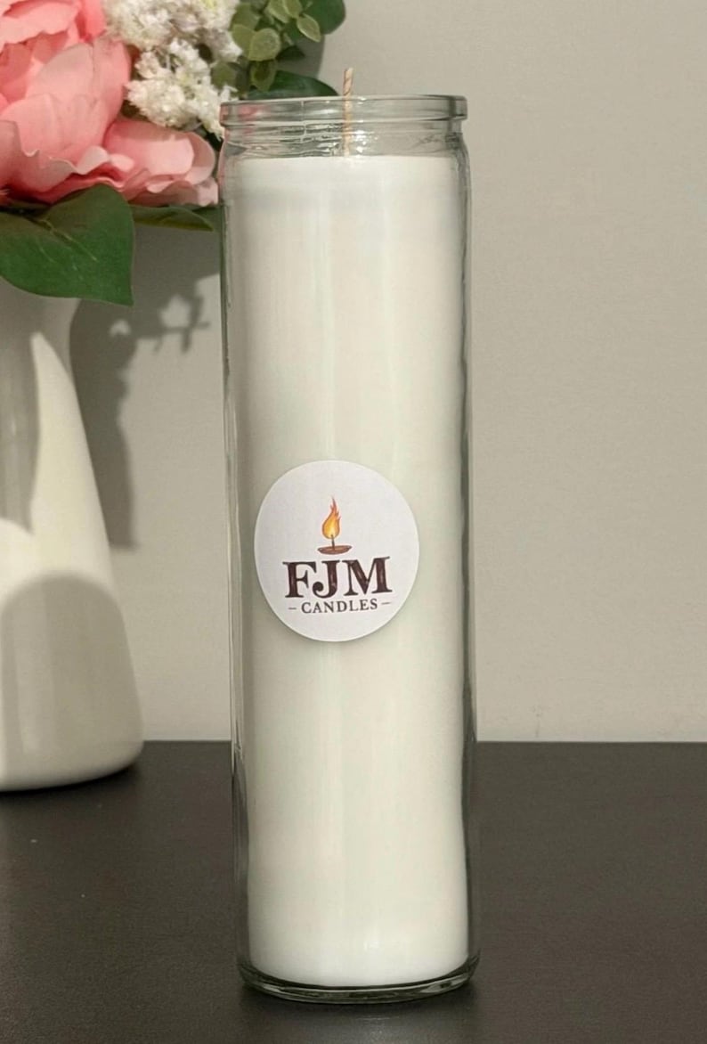 May include: A tall, cylindrical clear glass candle holder filled with solid white wax. A circular white sticker is centred on the glass, featuring a graphic of a lit candle flame above the brown text FJM - CANDLES in a serif font.