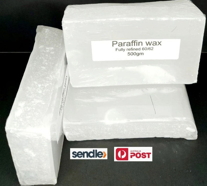 Puede incluir: Tres bloques blancos de cera de parafina, cada uno envuelto en pl&aacute;stico transparente. El bloque superior tiene una etiqueta que dice "Paraffin wax Fully refined 60/62 500gm".
