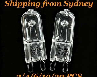 May include: Two clear G9 halogen light bulbs with a capsule shape. Each bulb features a visible internal filament and a base with two wire loops. Printed on the glass surface of each bulb is the text 230V 25W G9 CE along with a circular icon.