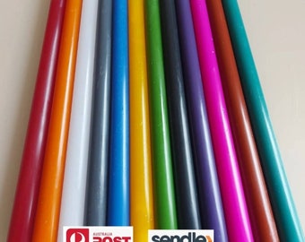 May include: Assortment of 12 long taper candles in various colors, including red, orange, yellow, green, blue, purple, white, gray, brown, and teal. The candles are arranged in a row, with the wicks facing the viewer.