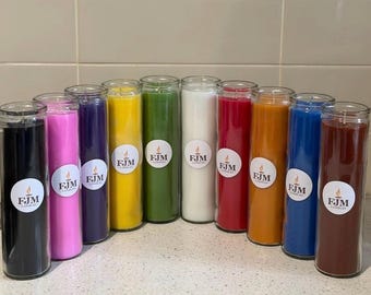 May include: A collection of ten tall cylindrical glass jar candles in various solid colors including black, pink, purple, yellow, green, white, red, orange, blue, and brown. Each candle features a circular white label with the text FJM CANDLES.