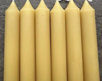 May include: Six tall, pale yellow taper candles with white wicks. The candles are arranged vertically, side by side, and have a smooth, cylindrical body with a conical top. The wicks are visible at the top of each candle.