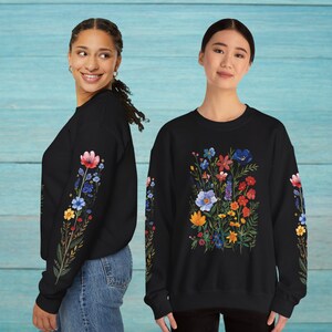 May include: Two black sweatshirts with floral embroidery. One sweatshirt has a single floral design on the left sleeve, the other has a larger floral design on the front.