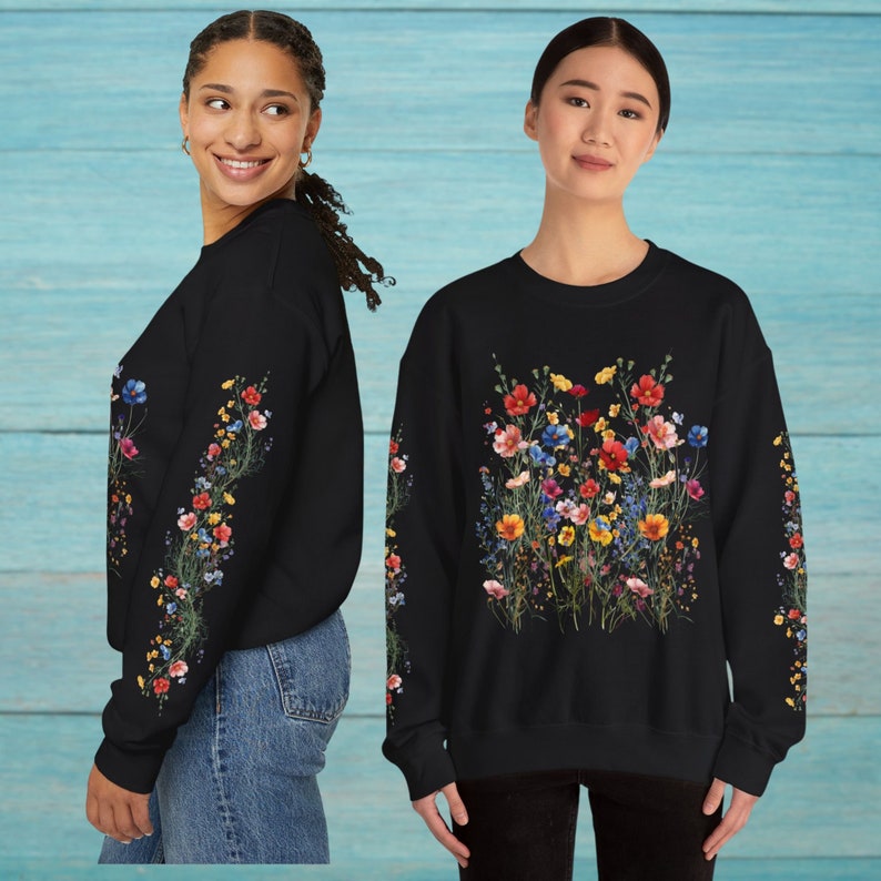Op de afbeelding: Zwart sweatshirt met een bloemenprint met verschillende kleurrijke bloemen. De bloemen zijn in een cluster in het midden van het sweatshirt en op de mouwen gerangschikt.