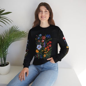 May include: A black sweatshirt with a colorful floral print. The flowers are in shades of red, orange, yellow, blue, and green. The sweatshirt has long sleeves and a crew neck.