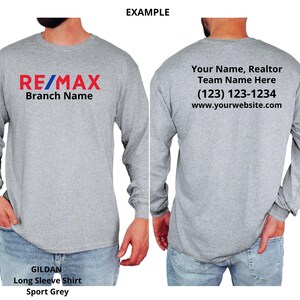 May include: Sport grey long sleeve shirt with the RE/MAX logo in red, blue, and white on the front. The back of the shirt has text that reads "Your Name, Realtor Team Name Here" with a phone number and website address. The shirt is a Gildan brand.