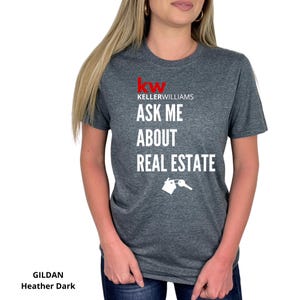 May include: Dark heather gray t-shirt with the text "Keller Williams ASK ME ABOUT REAL ESTATE" in white. The Keller Williams logo is in red. A white graphic of a house and key is below the text. The shirt is a Gildan Heather Dark.