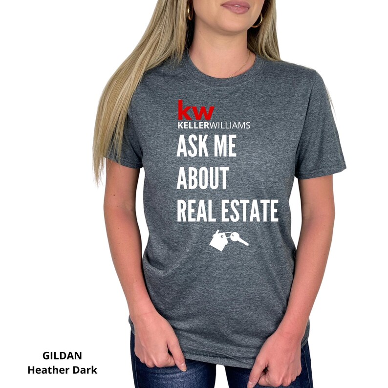 May include: Dark heather gray t-shirt with the text "Keller Williams ASK ME ABOUT REAL ESTATE" in white. The Keller Williams logo is in red. A white graphic of a house and key is below the text. The shirt is a Gildan Heather Dark.