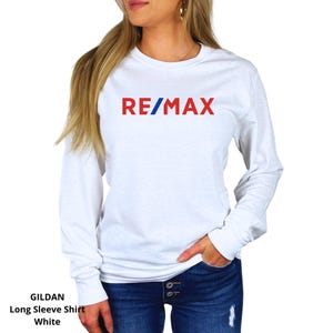 May include: White long sleeve shirt with the word "RE/MAX" in red and blue lettering across the chest. The shirt is a Gildan long sleeve shirt.