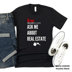 May include: Black heather t-shirt with the text "kw KELLERWILLIAMS ASK ME ABOUT REAL ESTATE" in white. The shirt also features a house and key graphic. White sneakers and blue jeans are also in the image.