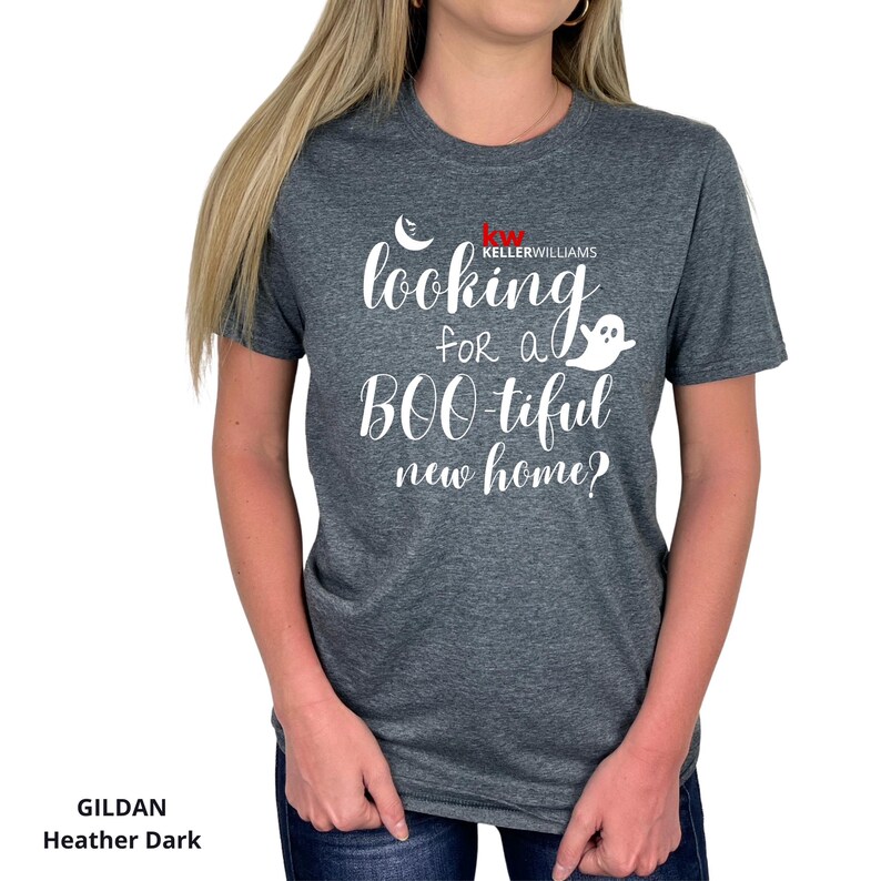 May include: A dark heather gray short-sleeve t-shirt featuring white text that reads "looking for a BOO-tiful new home?" with a small ghost graphic and a crescent moon. The shirt also includes the red and white Keller Williams logo text.
