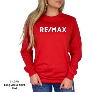 May include: Red long-sleeve shirt with the white text "RE/MAX" across the chest. The shirt is a Gildan brand long sleeve shirt. The shirt is red.