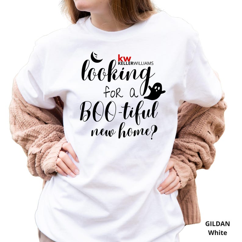 May include: A white Gildan t-shirt featuring black text that reads "looking for a BOO-tiful new home?" with a small black crescent moon, a ghost graphic, and the red and black "kw KELLERWILLIAMS" logo printed on the front chest area.