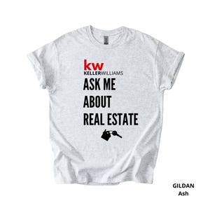 May include: Light gray Gildan Ash t-shirt with the Keller Williams logo in red and the text "ASK ME ABOUT REAL ESTATE" in black. A graphic of a house and key is below the text.