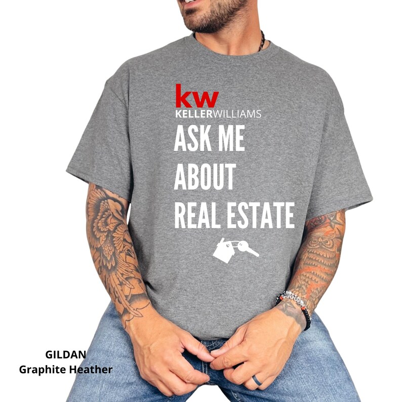 May include: Graphite heather t-shirt with the Keller Williams logo and the text "ASK ME ABOUT REAL ESTATE". The design includes a key graphic. The shirt is made by Gildan.