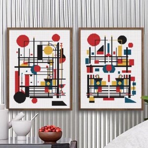 K&ouml;nnte beinhalten: Zwei gerahmte Wandbilder mit abstrakten geometrischen Kompositionen. Jeder Druck zeigt eine gitterartige Anordnung aus schwarzen Linien, ausgef&uuml;llten roten Kreisen, gelben Quadraten und blauen Rechtecken auf wei&szlig;em Grund, in d&uuml;nnen braunen Rahmen.