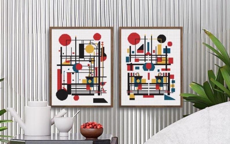 K&ouml;nnte beinhalten: Zwei gerahmte Wandbilder mit abstrakten geometrischen Kompositionen. Jeder Druck zeigt eine gitterartige Anordnung aus schwarzen Linien, ausgef&uuml;llten roten Kreisen, gelben Quadraten und blauen Rechtecken auf wei&szlig;em Grund, in d&uuml;nnen braunen Rahmen.