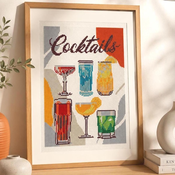 Peut inclure: Une œuvre d'art au point de croix encadrée représentant le mot "Cocktails" au-dessus de six illustrations de cocktails colorés. Les boissons sont représentées en rouge, bleu, jaune et vert, sur un fond géométrique.