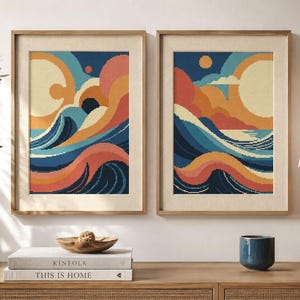 Puede incluir: Dos láminas de arte verticales enmarcadas que muestran un paisaje pixelado de olas oceánicas estilizadas, nubes y un sol en tonos azul marino, naranja, crema y azul claro. Las láminas están en marcos de madera clara con paspartú.