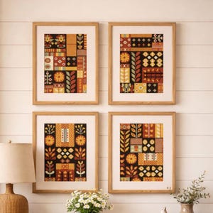 May include: Four framed art prints with a geometric pattern in shades of orange, yellow, and brown. The artwork features floral and abstract designs. The frames are made of light-colored wood, and the prints are displayed on a white wall.