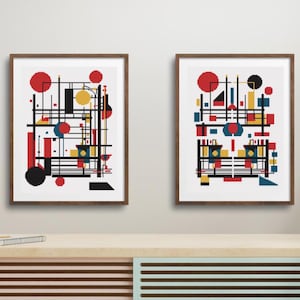 K&ouml;nnte beinhalten: Zwei gerahmte Wandkunstdrucke mit abstrakten geometrischen Kompositionen. Jeder Druck zeigt eine komplexe Anordnung aus schwarzen Linien sowie roten, gelben und blauen Kreisen, Quadraten und Rechtecken auf wei&szlig;em Hintergrund in dunkelbraunen Holzrahmen.