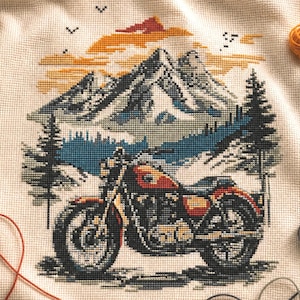 May include: Cross-stitch design featuring a motorcycle in front of a mountain landscape. The artwork uses shades of orange, blue, and green. The motorcycle is the focal point, with detailed stitching. The background includes mountains, trees, and a lake.