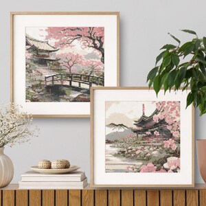 Può includere: Due stampe incorniciate raffigurano un paesaggio giapponese con una pagoda, un ponte e fiori di ciliegio. L'opera d'arte presenta tenui tonalità rosa, verdi e marroni, creando una scena serena. Le stampe sono esposte su una superficie di legno.