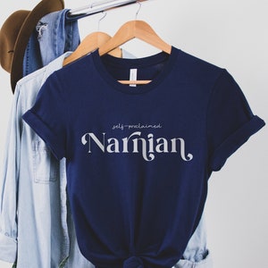 May include: A navy blue t-shirt with the text "self-proclaimed Narnia" in white lettering.
