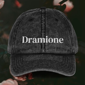 May include: Black vintage washed denim baseball cap with white embroidered text that reads "Dramione".