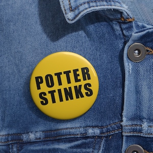 May include: A yellow button with the text "POTTER STINKS" in black letters. The button is pinned to a blue denim jacket.