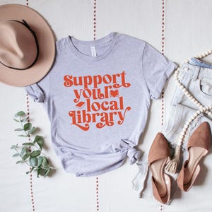 gray t shirt with red text support your local library