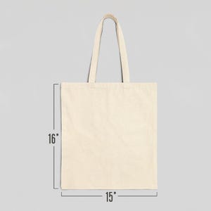 May include: A plain, off-white canvas tote bag with two handles. The bag measures 15 inches wide by 16 inches tall.