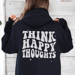 以下が含まれることがあります： 背面に「Think Happy Thoughts」という白いレトロな文字で書かれた黒いフード付きスウェットシャツ