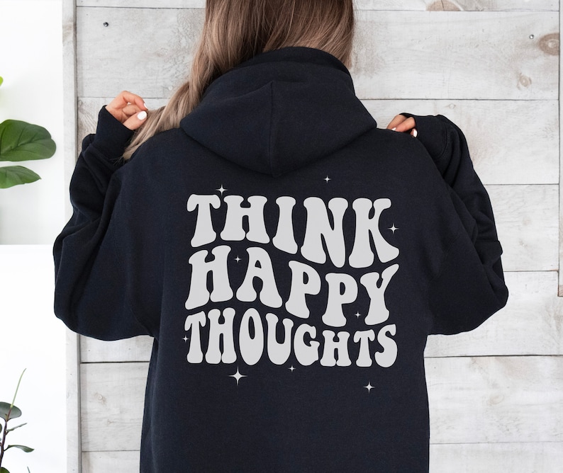 以下が含まれることがあります： 背面に「Think Happy Thoughts」という白いレトロな文字で書かれた黒いフード付きスウェットシャツ