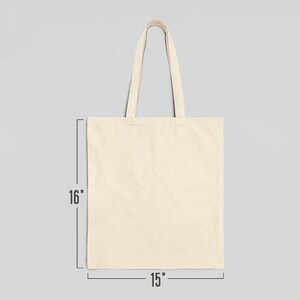 May include: A plain, off-white canvas tote bag with two handles. The bag is 15 inches wide and 16 inches tall.