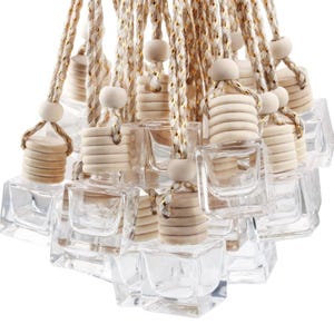 Könnte beinhalten: Eine Gruppe von quadratischen Glasflaschen aus klarem Glas mit Holzstopfen und Bindfäden. Die Flaschen hängen zusammen und eignen sich perfekt zum Herstellen von Lufterfrischern für Autos.