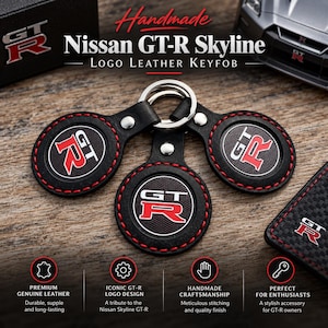 Pode incluir: Três porta-chaves circulares em couro preto com o logótipo Nissan GT-R em vermelho e branco. Cada porta-chaves tem costuras vermelhas à volta do rebordo e está preso a um anel de metal prateado. O texto Nissan GT-R Skyline Logo Leather Keyfob é visível.